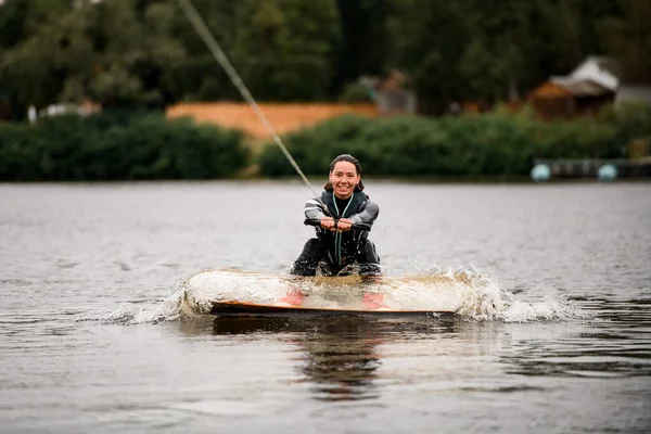 Θηλυκό wakeboarder αρχίσει να βόλτες στο νερό κρατώντας σχοινί από μηχανοκίνητο σκάφος — Φωτογραφία Αρχείου