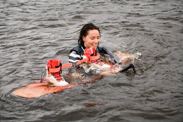 밝은 웨이크 보딩 보드를 신고 물 속에서 수영하는 여성 — 스톡 사진