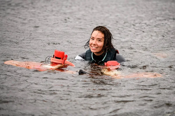 Όμορφη νεαρή γυναίκα κολυμπά στο νερό με γιλέκο με φωτεινό wakeboarding σκάφους — Φωτογραφία Αρχείου