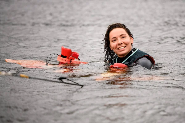 Χαρούμενη νεαρή γυναίκα κολυμπά στο νερό με γιλέκο με φωτεινό wakeboarding σκάφους — Φωτογραφία Αρχείου