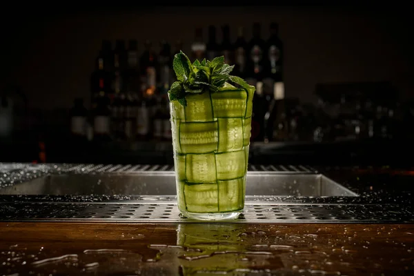 Schönes Glas geflochten mit grünen Gurken mit einem Zweig frischer Minze — Stockfoto