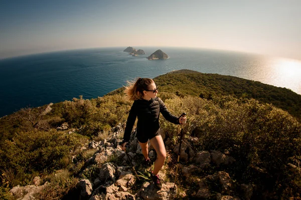 Deniz manzaralı yürüyüş direkleri olan çekici bir kadının panoramik görüntüsü