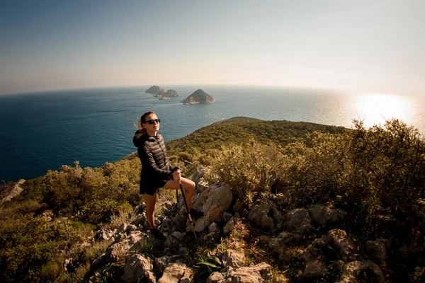 Panoramisch uitzicht op mooie vrouw met wandelpalen op zeegezicht achtergrond — Stockfoto