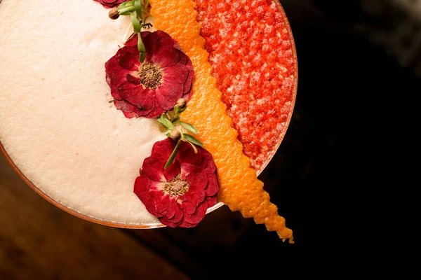 Zbliżenie pięknych suszonych kwiatów i skórki pomarańczy zdobiące szklankę piankowego koktajlu — Zdjęcie stockowe