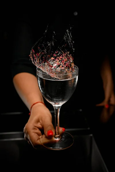 Mano femenina sostiene vidrio con líquido decorado con hebras de caramelo con pétalos de flores — Foto de Stock