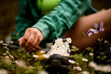 Kadınların spor ayakkabılarına dizilmiş küçük papatya çiçeklerine odaklan