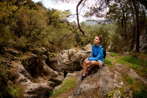 Dromen vrouw zitten in het bos op de rand van een rotsachtige klif — Stockfoto