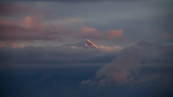 Incrível bela vista do pico de montanha branco coberto de neve entre as nuvens — Fotografia de Stock