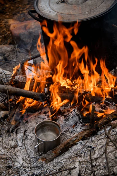 Top view of fire with saucepan and steel mug with water at it. — Stock Photo, Image