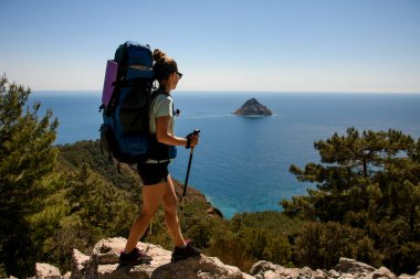 Deniz manzaralı arka planda sırt çantasıyla gezen kadın turistin harika bir yan görüntüsü.