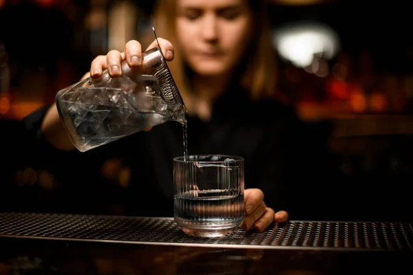 Mano del camarero sostiene la taza de cristal de mezcla con cóctel y lo vierte en vidrio transparente a la antigua — Foto de Stock