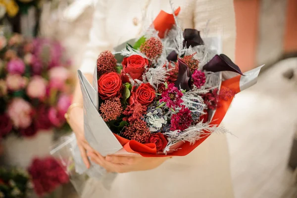 Primer plano del ramo de rosas y ramas plateadas y coloreadas empaquetadas en papel de regalo — Foto de Stock