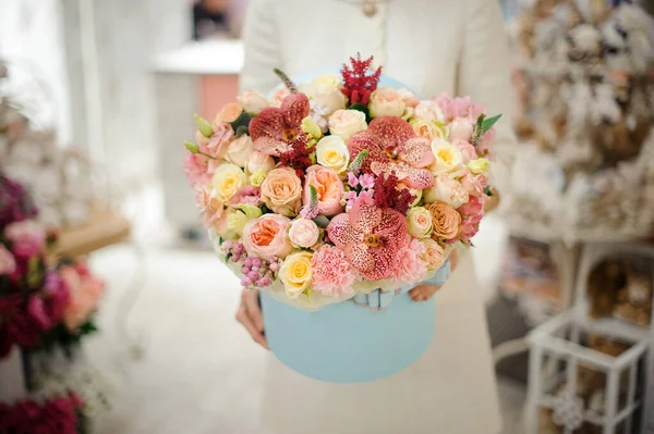 Close-up de belo arranjo floral de rosa orquídeas e cravos na caixa nas mãos da mulher — Fotografia de Stock