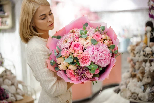 Hermosa mujer sostiene gran ramo de hortensias de crisantemo rosa y rosas — Foto de Stock