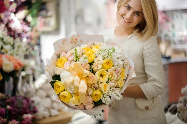 Mujer rubia feliz con ramo de rosas flores embaladas en papel y decoradas con cinta —  Fotos de Stock