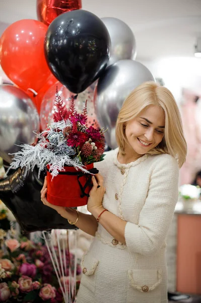 ผู้หญิงที่มีความสุขที่มีกล่องกลมของการจัดดอกไม้ในมือของเธอ สีแดงและสีเงิน . — ภาพถ่ายสต็อก
