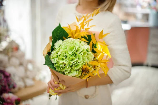 Schöner Hortensienstrauß und leuchtend gelbe Zweige in den Händen der Frau — Stockfoto