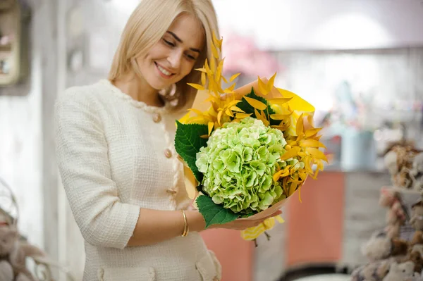 Hermoso ramo de hortensias y ramas amarillas en las manos de la mujer sonriente — Foto de Stock