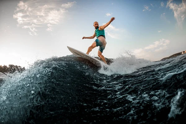 Hombre deportivo en chaleco salvavidas turquesa está surfeando en la tabla de surf en el río —  Fotos de Stock