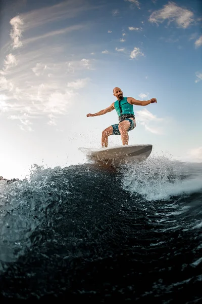 Hombre adulto activo equilibrándose en tabla wakesurf en la ola salpicadura —  Fotos de Stock