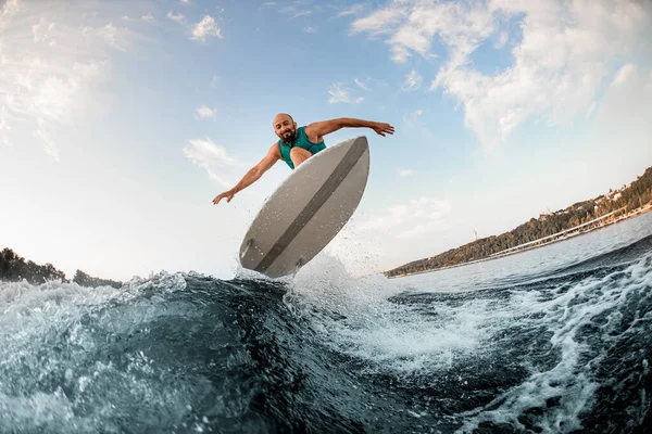 Gran vista del hombre en wakeboard mientras salta hábilmente sobre salpicar ola del río contra el cielo azul. —  Fotos de Stock