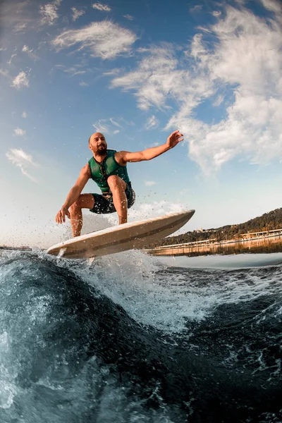 Olahragawan di atas kapal sementara terampil melompat melompati percikan gelombang sungai terhadap langit biru. — Stok Foto