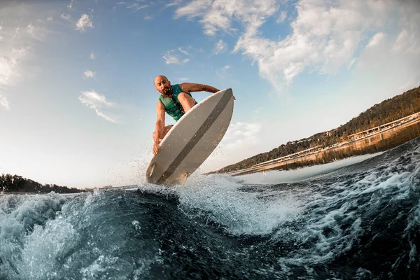 Wspaniały widok sportowca na wakeboard podczas umiejętnie skoków nad rozpryskującej fali rzeki o błękitne niebo. — Zdjęcie stockowe