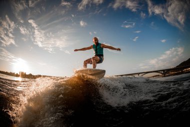 Nehirde dalgalar halinde mavi gökyüzüne ve köprüye karşı yürüyen enerjik sporcu.