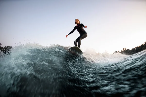 Wakesurfer féminin athlétique équilibré sur la planche sur la vague de la rivière — Photo