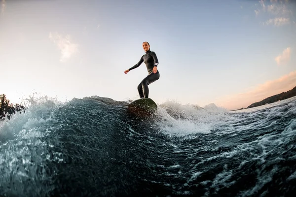 Femme athlétique wakesurf sur la planche en bas de la rivière sur le fond du ciel bleu — Photo