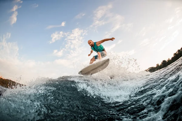 Mann springt auf Wake Board die Wellen des Flusses hinunter. Männlicher Athlet beim Wakesurf-Training. — Stockfoto