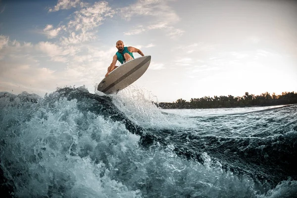 Vista incrível de onda salpicando e homem habilmente pulando sobre ele no wakeboard — Fotografia de Stock