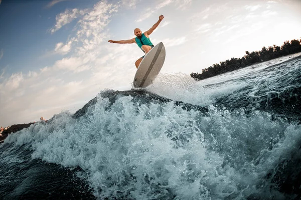 Herrliche Aussicht auf plätschernde Welle und Mann, der gekonnt auf Wakeboard drüber springt — Stockfoto