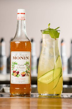 UKRAINE, KYIV - 11 Mart 2021: Masanın üzerinde soğuk kokteyl bulunan bir şişe Monin çarkıfelek şurubu ve cam sürahi seçici odak noktası