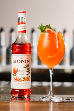 UKRAINE, KYIV - 11 Mart 2021: Barın üzerinde kokteyl bulunan güzel bir şişe Portakal Spritz şurubu ve cam manzarası