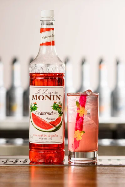 UKRAINE, KYIV - 11 maart 2021: Close-up van fles Monin watermeloensiroop en glas met koude cocktail op tafel — Stockfoto