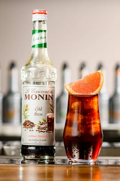 UKRAINE, KYIV - 11 maart 2021: Close-up van fles Koude Brew Siroop van Monin en glas cocktail met citrusschijfje — Stockfoto