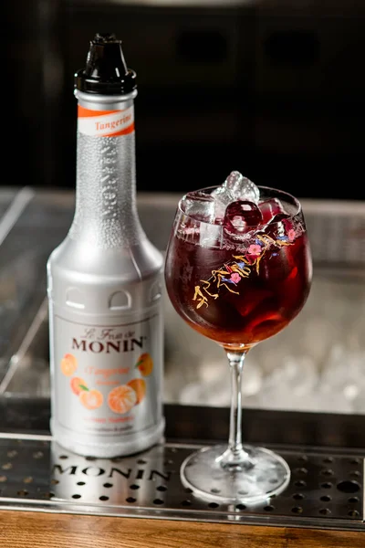 UKRAINE, KYIV - 11 maart 2021: hoge hoek uitzicht op fles mandarijnstroop van Monin en mooi glas koude cocktail — Stockfoto