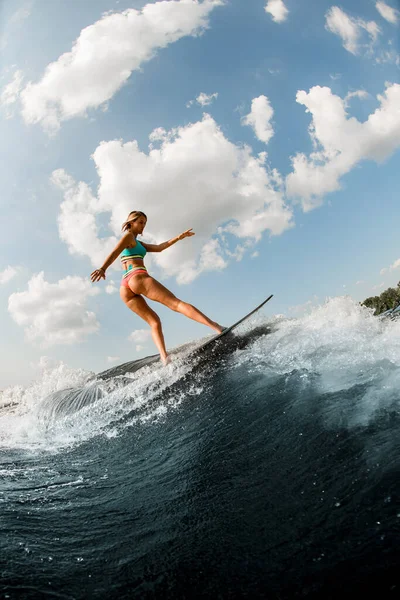 Hermosa mujer wakesurfer hábilmente equilibrio a bordo a lo largo de la ola del río —  Fotos de Stock