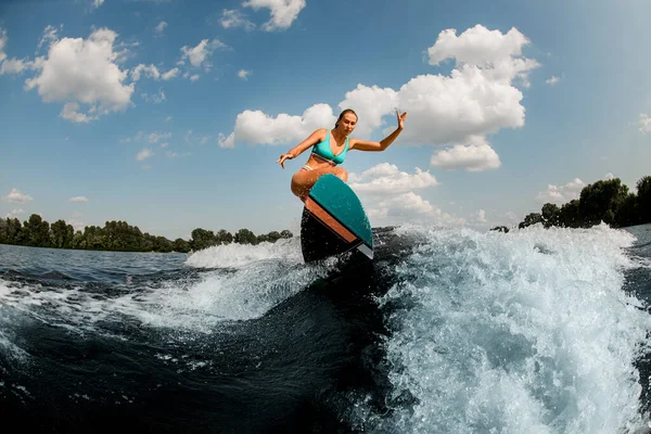 Femme de wakeboard actif wakesurfer sautant habilement avec wakeboard à éclabousser vague de rivière — Photo