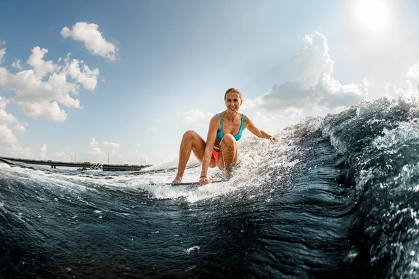 Sonriente joven mujer cabalga por la ola en un wakeboard —  Fotos de Stock