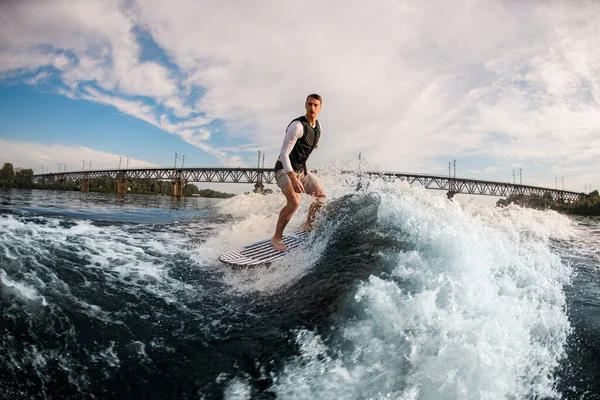 Armloser Mann reitet auf der Welle auf dem Wakeboard vor dem wolkenverhangenen Himmel. — Stockfoto