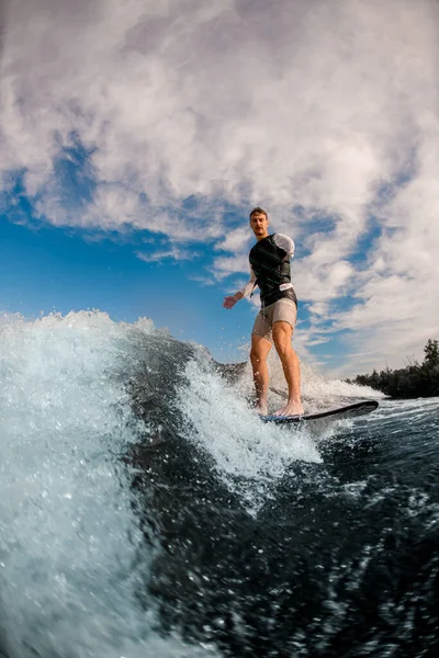 Homem de um braço montar a onda no wakeboard contra o fundo do céu nublado. — Fotografia de Stock