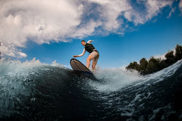 Enarmad idrottsman står på surfbrädet och rider på vågen. Vaknar på floden — Stockfoto