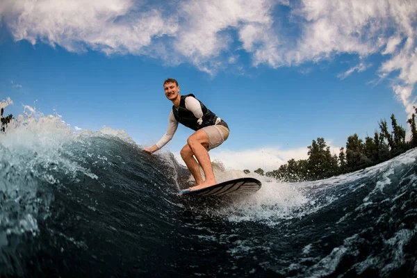 Uomo senza braccia wakesurfing sul bordo giù l'onda sullo sfondo del cielo — Foto Stock