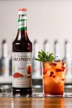 UKRAINE, KYIV - 12 Mart 2021: Monin rooibos konsantresi ve bar tezgahında serinletici bir kokteyl şişesinin önü