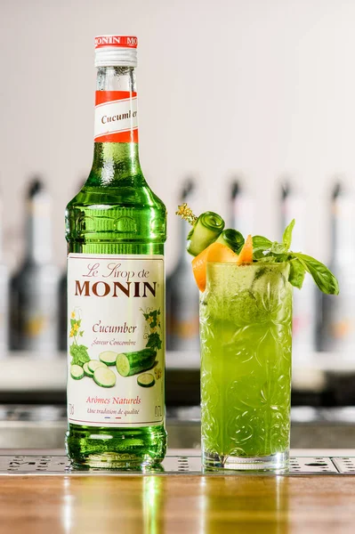 UKRAINE, KYIV - 12 maart 2021: fles Monin komkommer siroop en glas koude groene cocktail op bar — Stockfoto