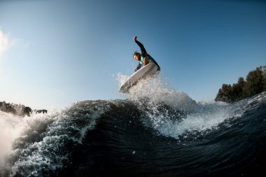 wakesurfer aktif olarak mavi gökyüzünün arka planında yüksek dalgaların üzerine atlıyor