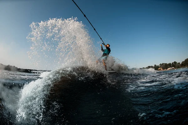 Hombre activo cabalgando en el wakesurf sosteniendo la cuerda de la lancha a motor en el fondo del cielo azul — Foto de Stock