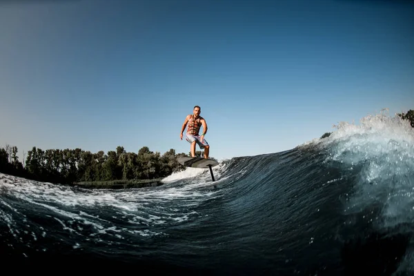 Чудовий вид на дорослого чоловіка, який катається на хвилі з фольгою з гідрофольги на фоні блакитного неба — стокове фото